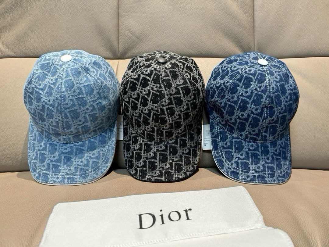 Three Dior logo-print caps: two dark blue and one black, side-by-side on a couch.