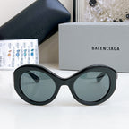 Balenciaga sunglasses with black oval frames and dark gray-tinted lenses