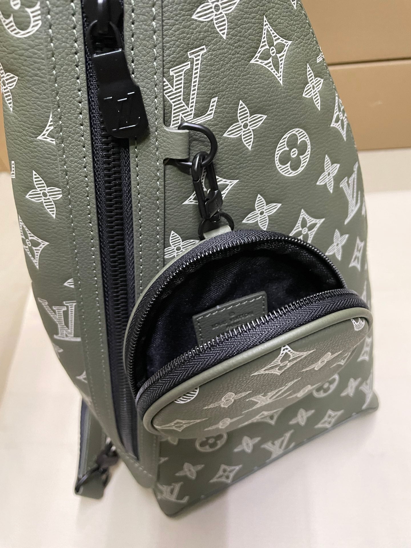 Louis Vuitton monogram sling bag detail, zipper pull and black interior pocket