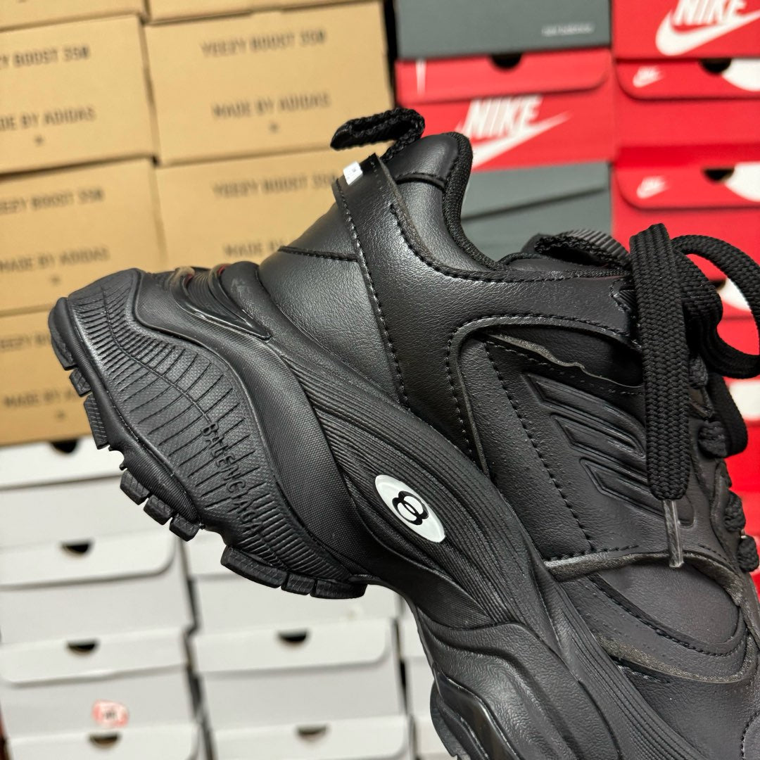 Black Balenciaga unisex sneaker side view with thick rubber sole tread and logo detail