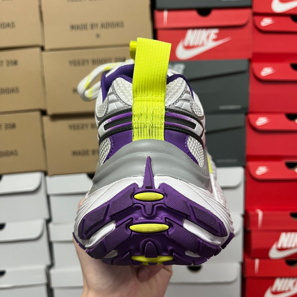 White and gray sneaker with purple overlays and neon green strap on top.