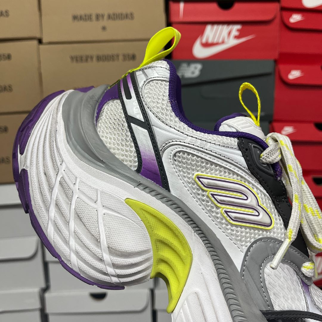 White mesh sneaker with black detail, purple panel, and neon green oval logo.