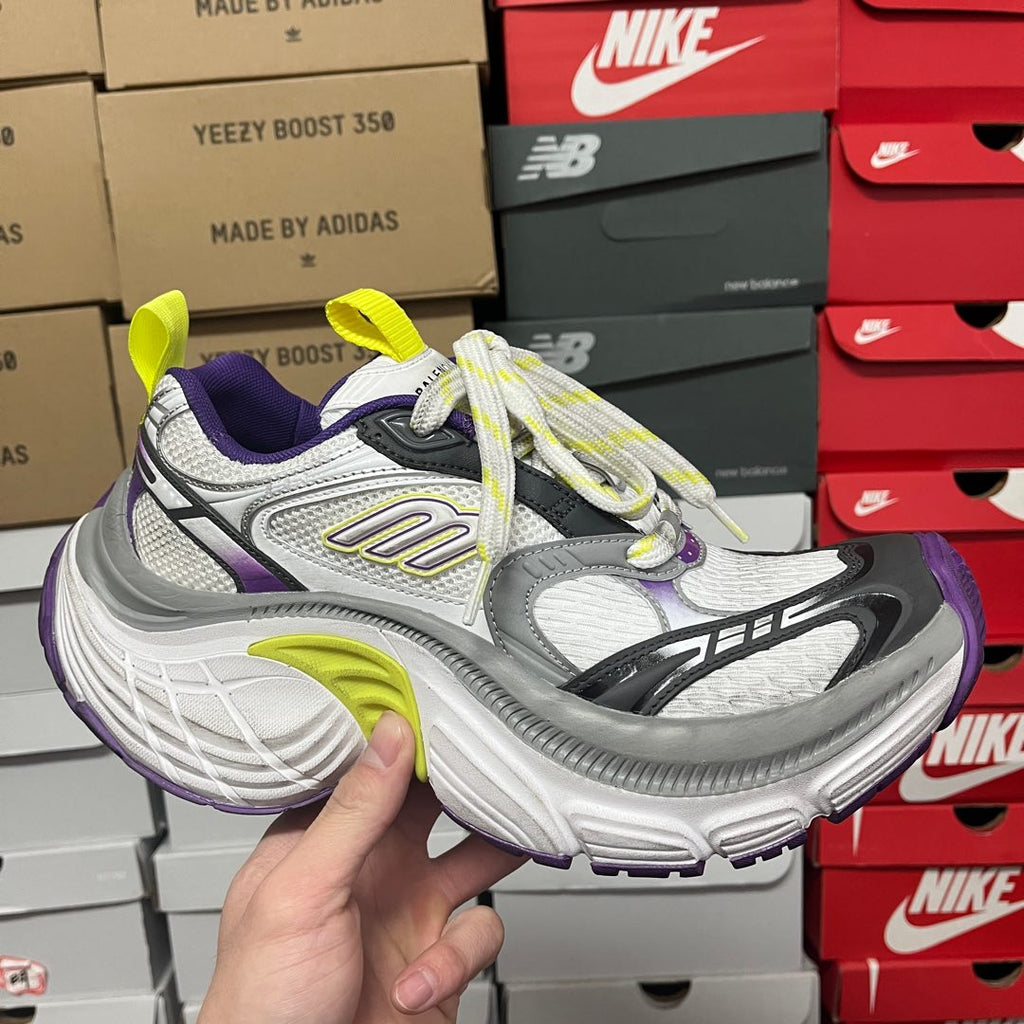 White and gray sneaker with black stripes, purple and neon green accents.