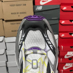 Heel opening of white and gray sneaker with black detailing and purple collar.