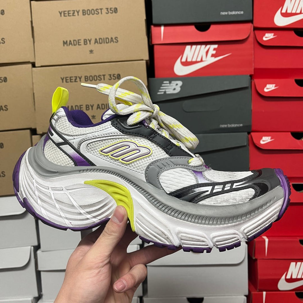 White and gray sneaker with black stripes, purple heel, and neon green laces.
