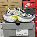 White and gray running sneaker with purple heel and neon green laces.