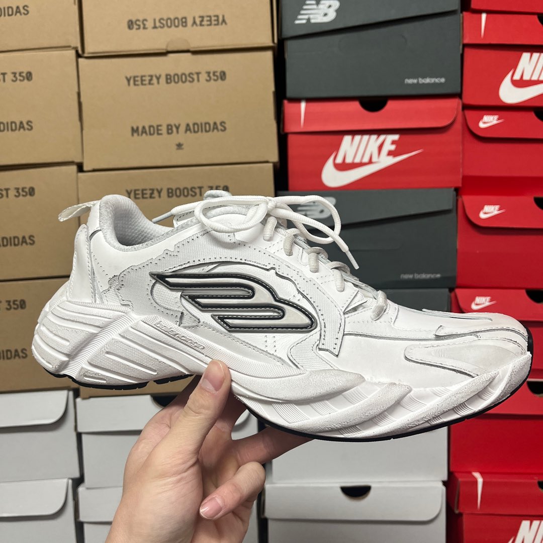 White lace-up athletic sneaker with raised black logo detail on side