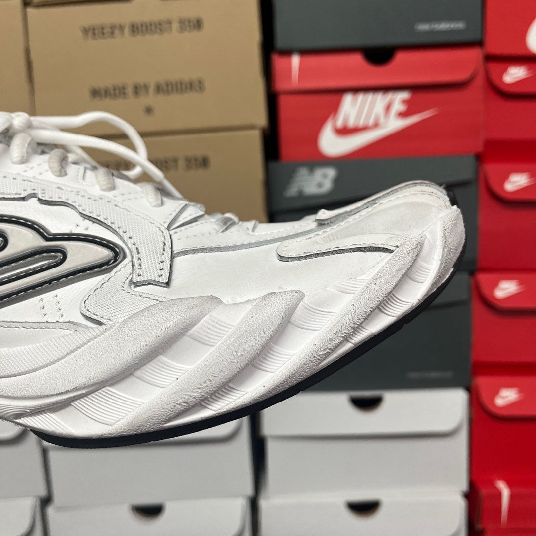 White athletic sneaker showing side profile and ribbed cushioning sole