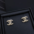 Pair of silver-tone Chanel CC stud earrings with rhinestone clusters on dark display