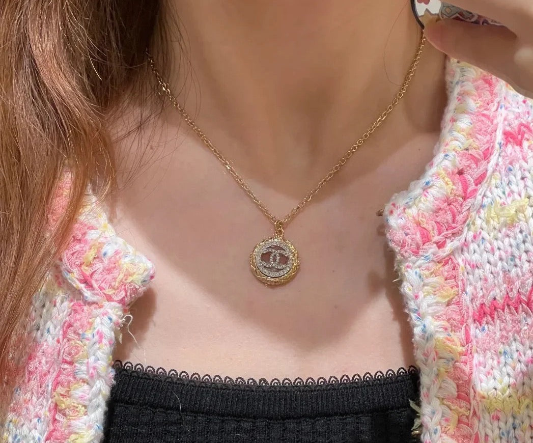 Gold-tone Chanel CC pendant necklace worn with black camisole