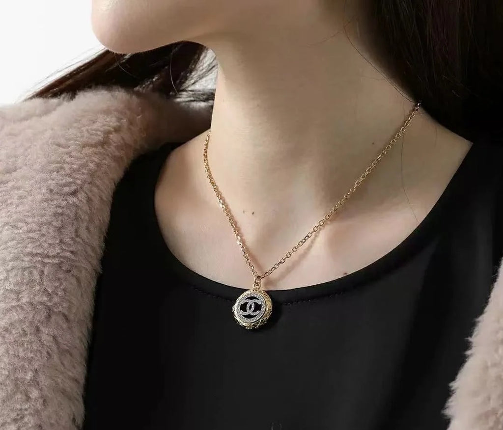 Gold-tone Chanel CC pendant necklace worn with black top and faux-fur jacket