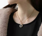 Gold-tone Chanel CC pendant necklace worn with black top and faux-fur jacket