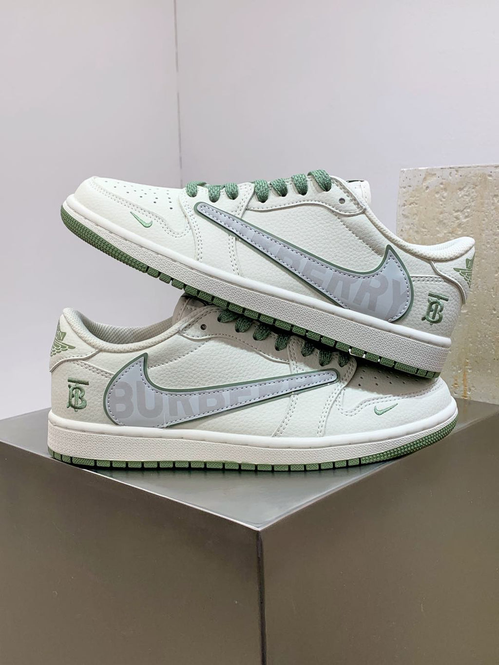 Burberry sneakers stacked on box, white leather with green lace trim and swoosh detail