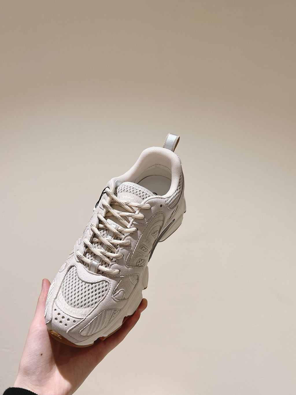 White Dior unisex sneaker held, side profile with lace-up eyelets and padded collar