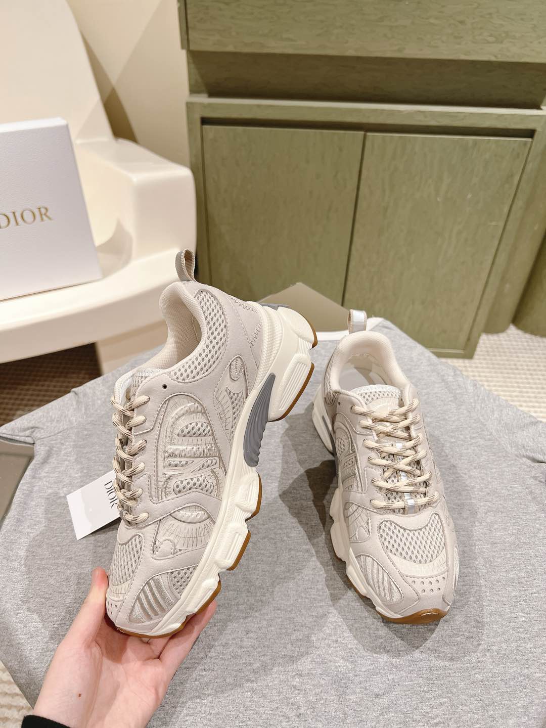 White Dior unisex sneakers, one foot angled, showing side mesh and chunky sole