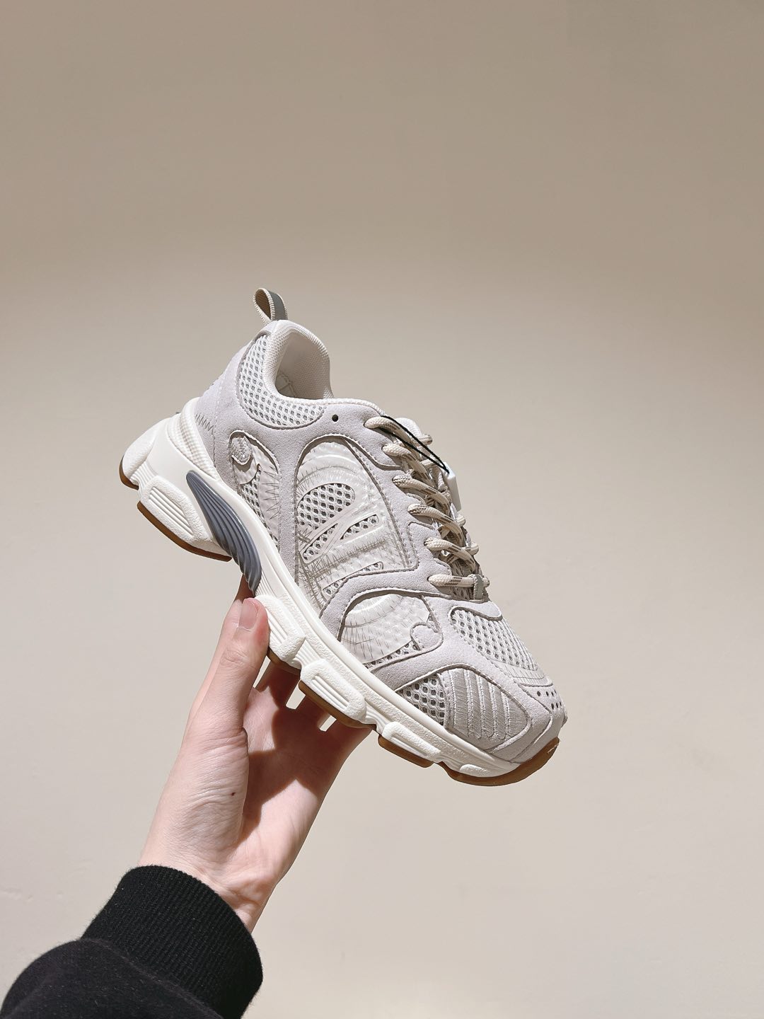 White Dior unisex sneaker held in hand, lace-up front and thick sole