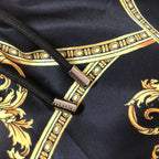 Versace swim shorts close-up of black fabric with gold and orange trim and logo tag
