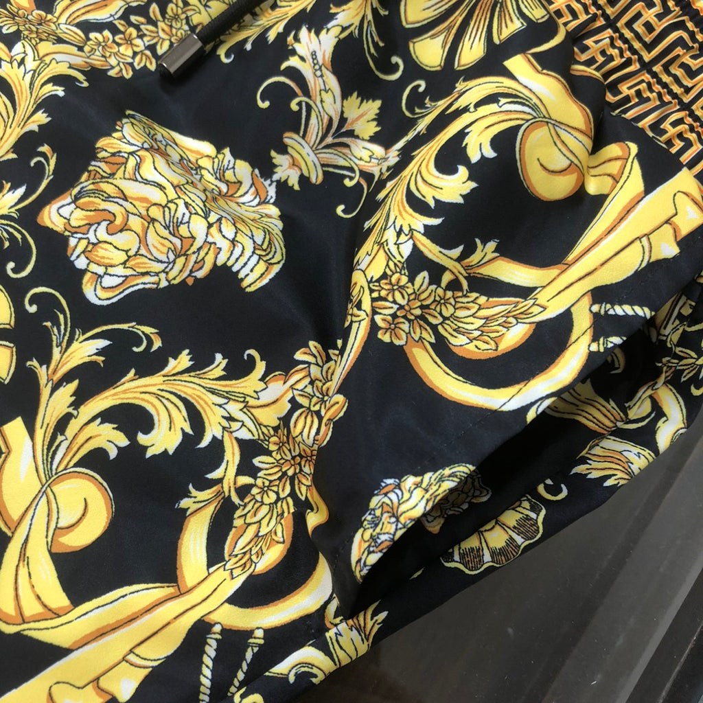 Close-up of black fabric with ornate gold baroque floral prints on the shorts.