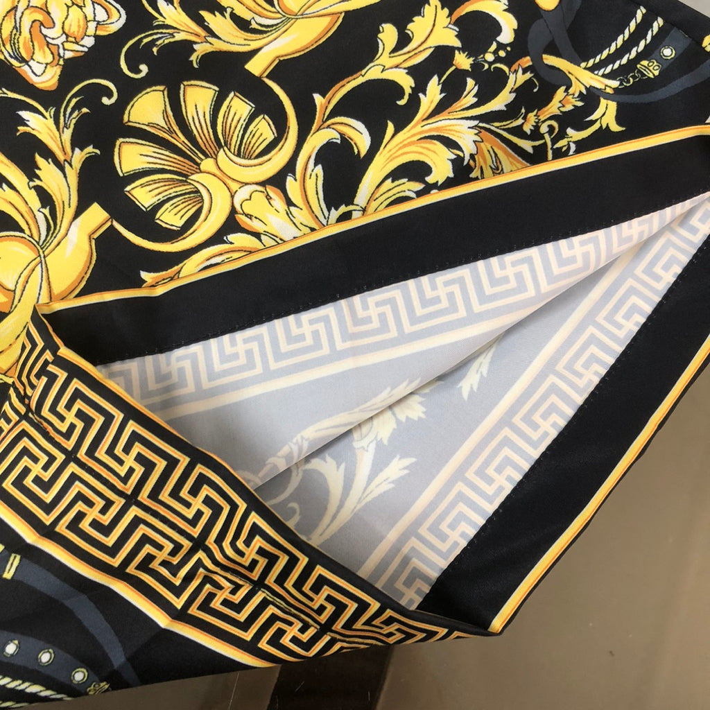 Folded shorts showing black-and-gold Greek key trim and light interior lining.