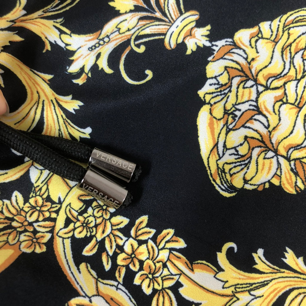 Black shorts detail with small Versace logo tag and baroque gold floral pattern.