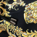 Black shorts detail with small Versace logo tag and baroque gold floral pattern.