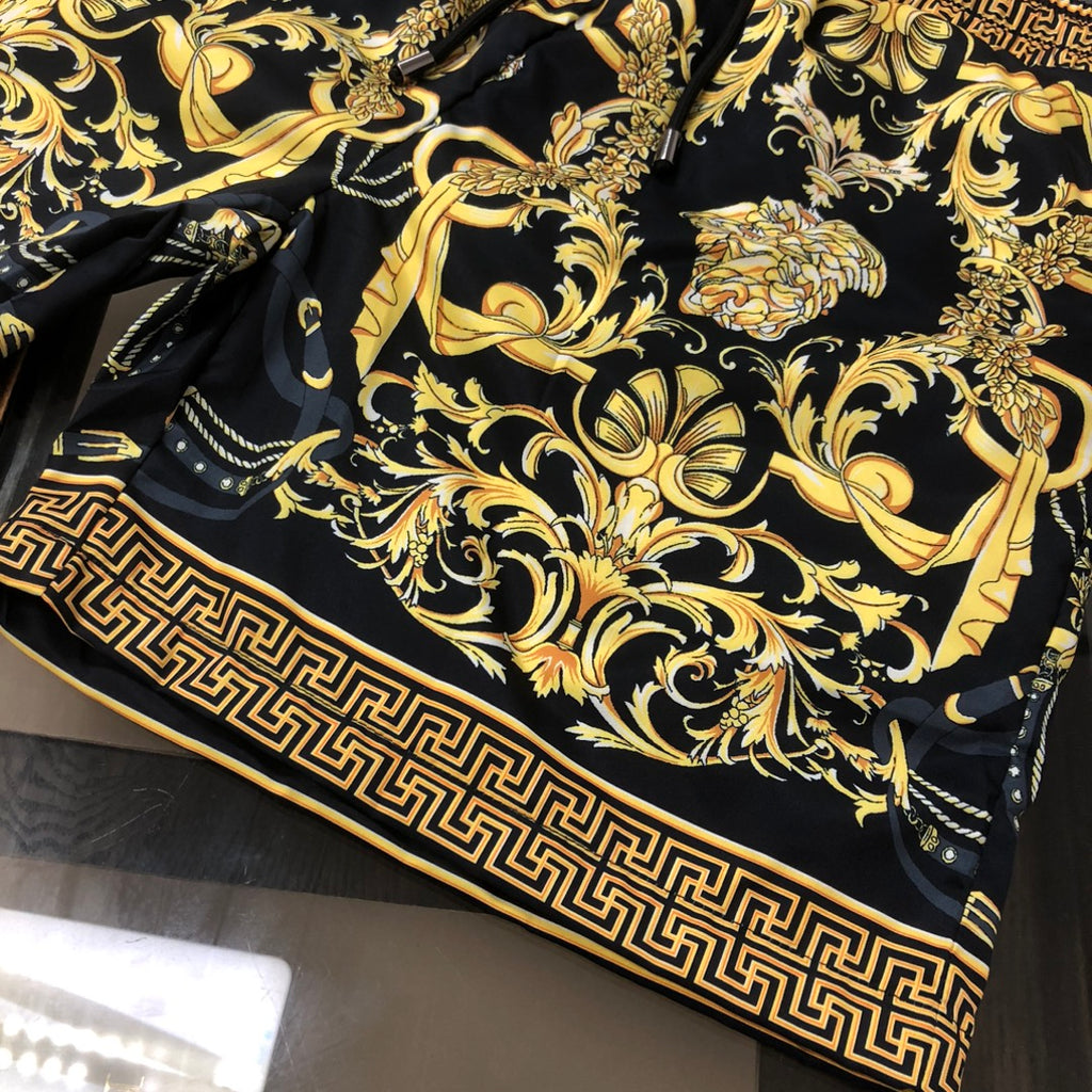 Black shorts with gold baroque print and Greek key trim along the hem border.