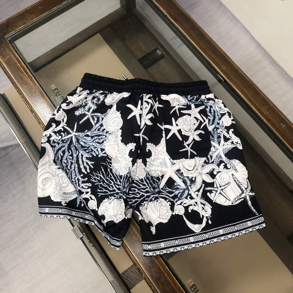 Printed shorts with black base, white baroque figures, drawstring waist, and trim hem