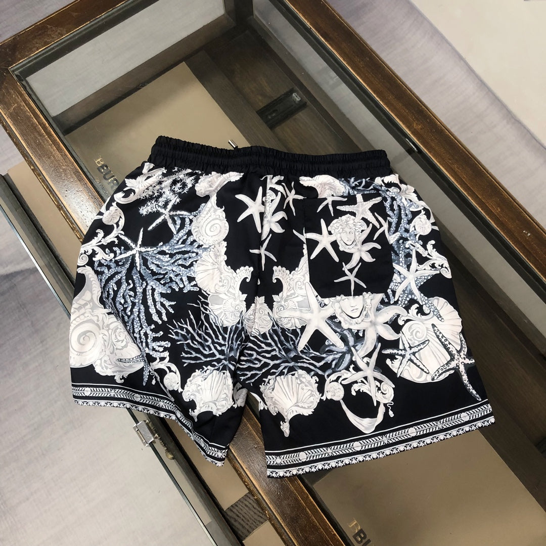 Printed shorts with black base, white baroque figures, drawstring waist, and trim hem