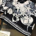 Printed shorts with black base, white baroque figures, and striped trim along hem