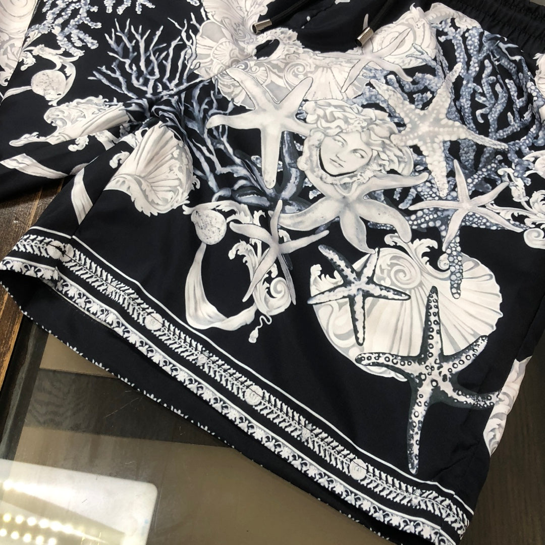 Printed shorts with black base, white baroque figures, and striped trim along hem