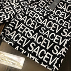 Versace logo shorts laid flat in black with white repeating VERSACE print