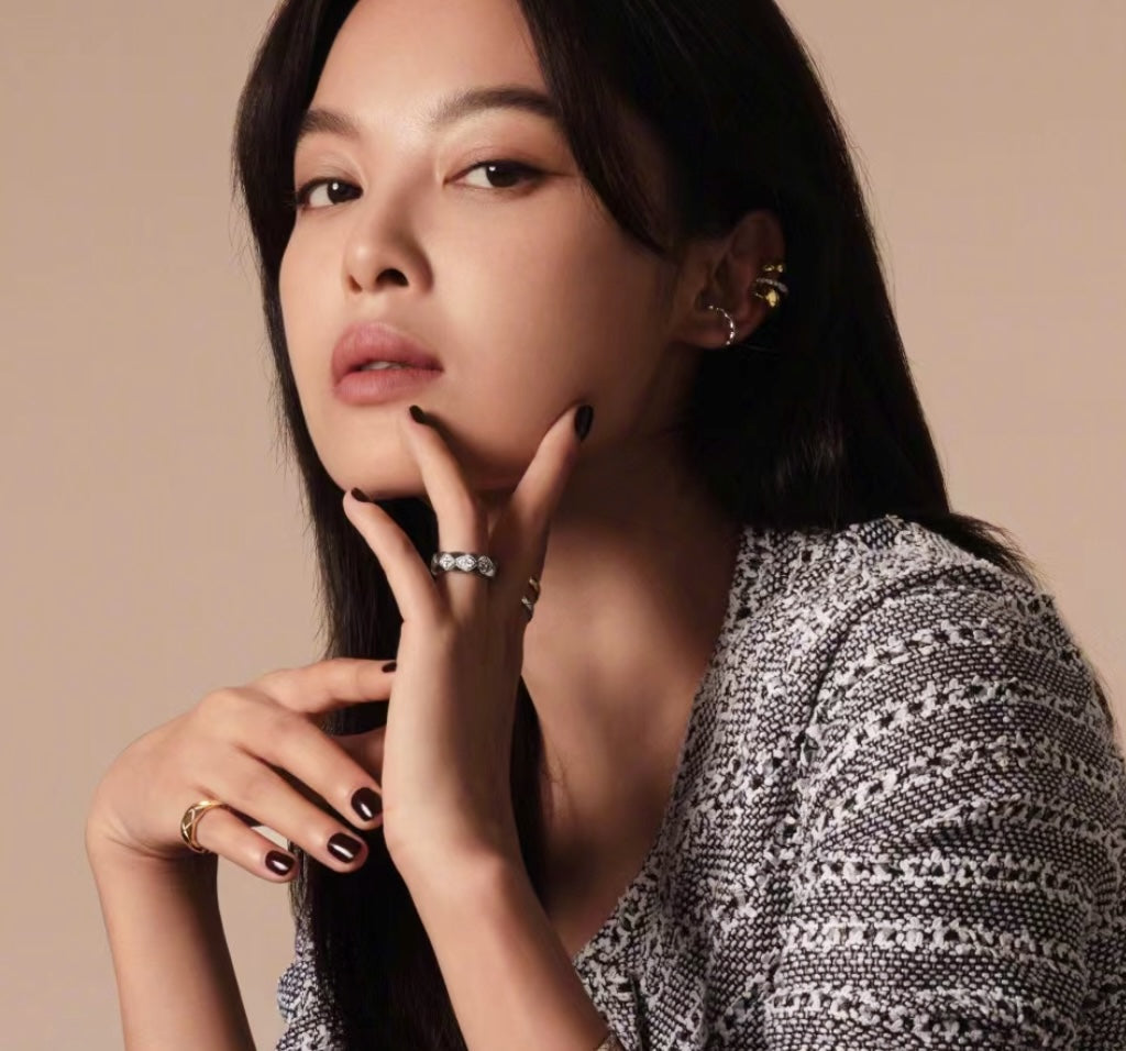 Gold-tone ring with stone bezel detail on finger, shown with bracelets and earrings