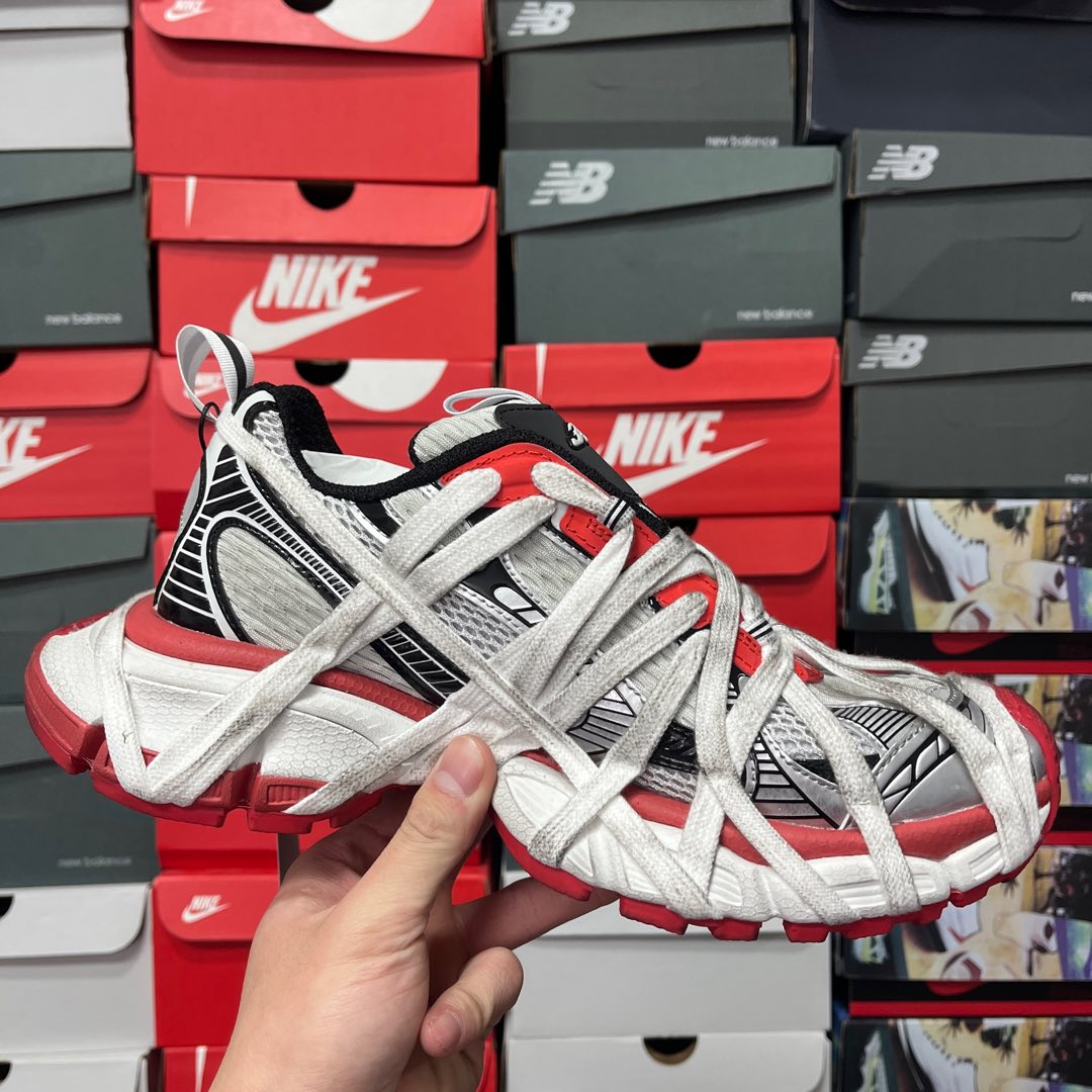 Unisex sneakers angled view with lace-up front, white mesh panels, and red sole