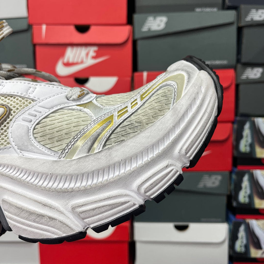 White sneaker side with gold trim and black-edged outsole with chunky tread