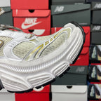 White sneaker side with gold trim and black-edged outsole with chunky tread