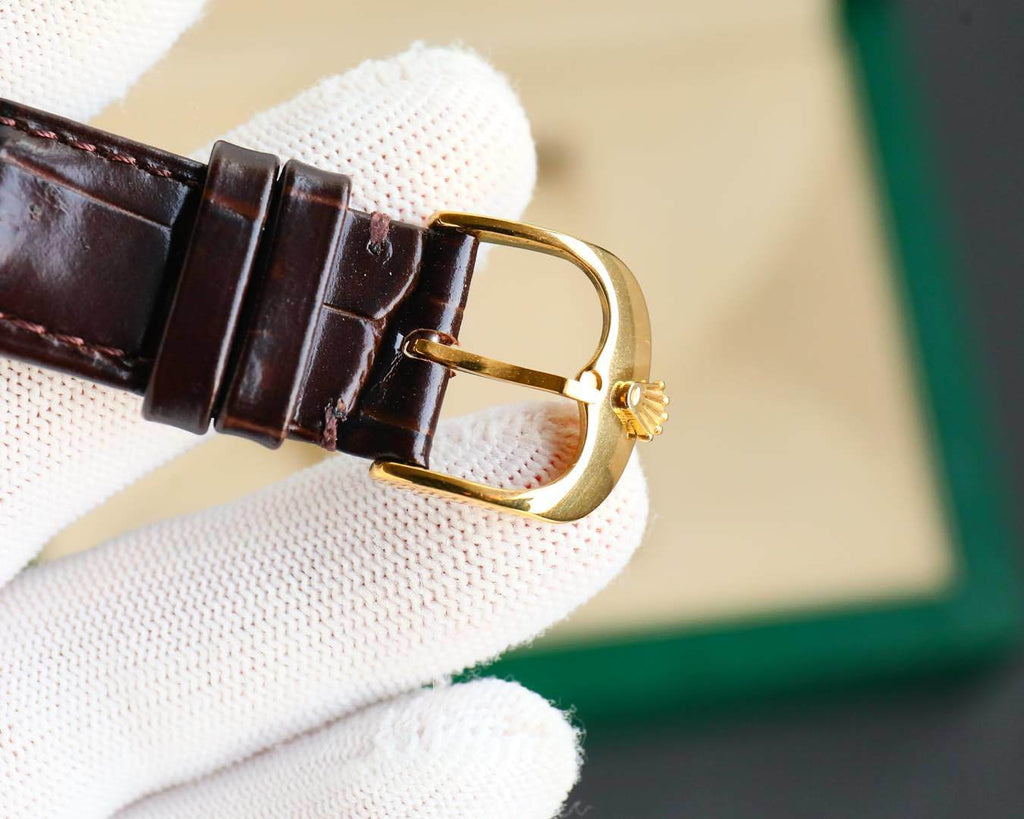 Rolex watch side profile with gold-tone buckle and brown leather strap