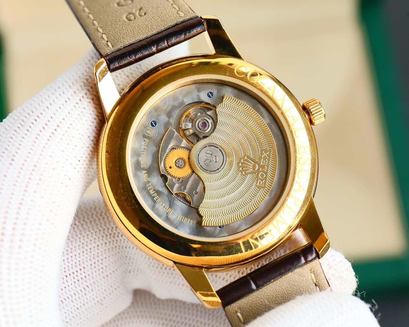 Rolex watch with open case back showing gears, gold-tone rim, brown leather strap