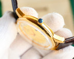 Rolex watch crown with blue cabochon set in gold-tone case, brown leather strap