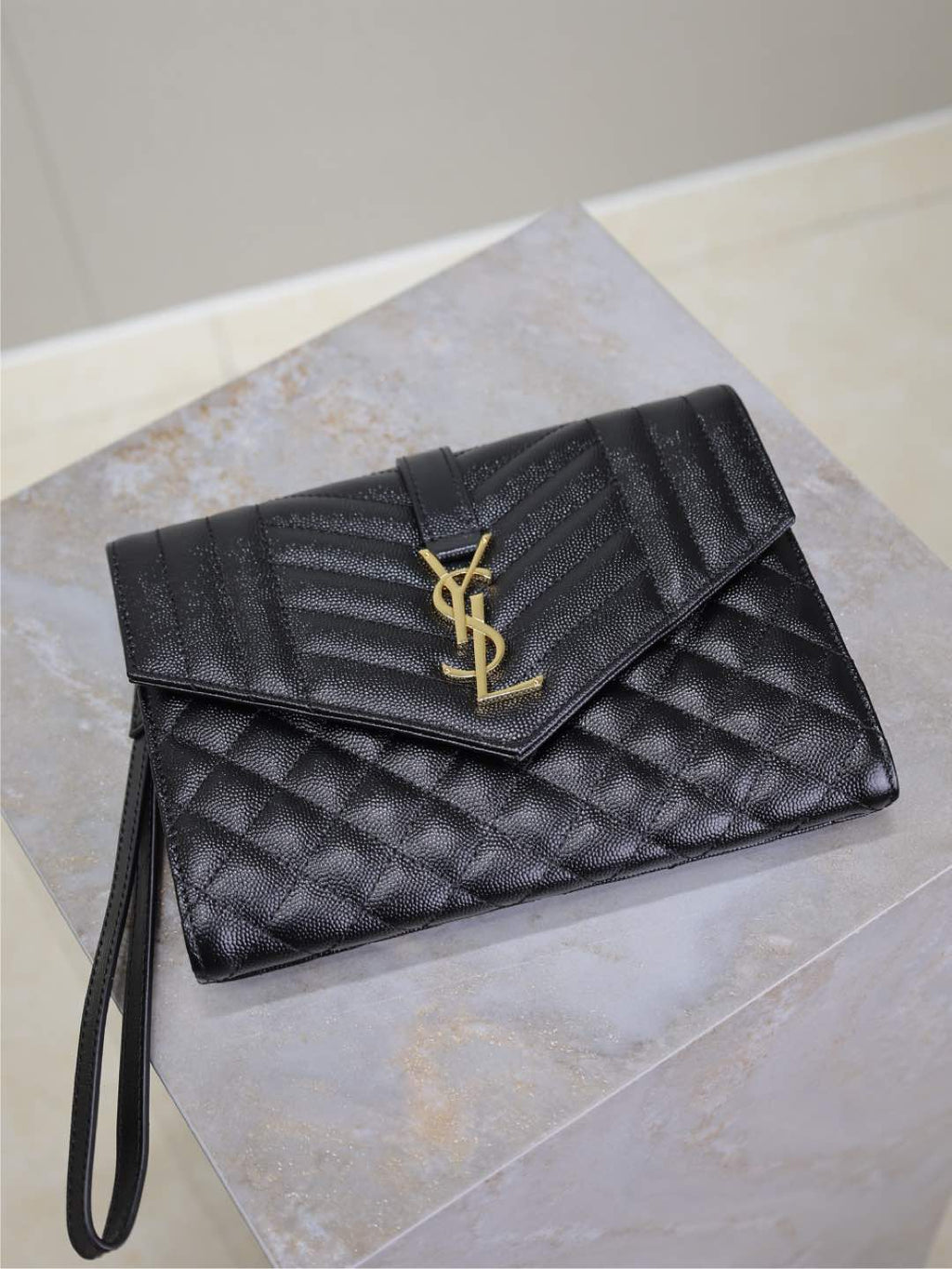 Black quilted YSL envelope flap bag with gold-tone YSL logo and wrist strap