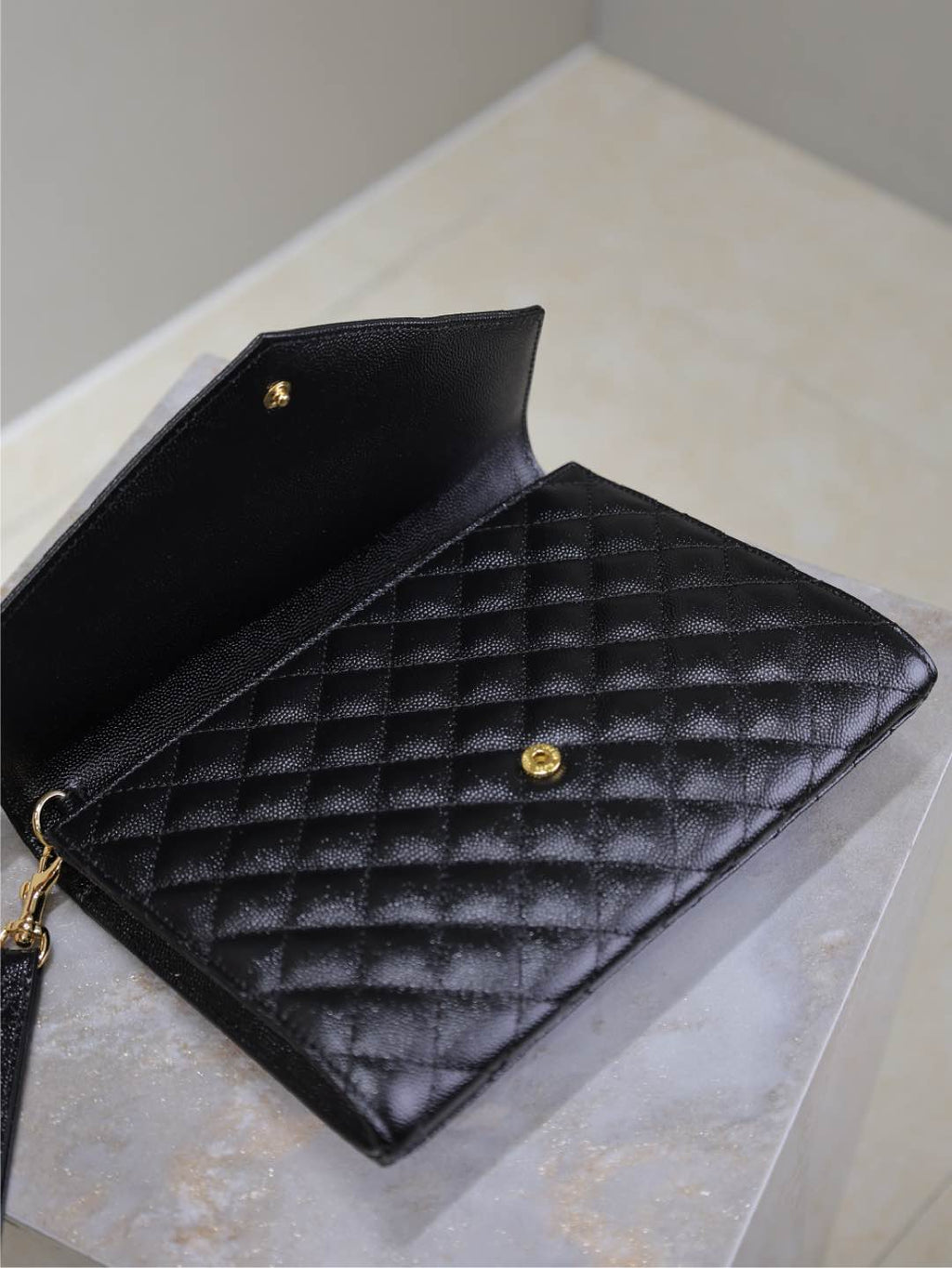 Black YSL quilted flap bag interior with snap and gold-tone hardware