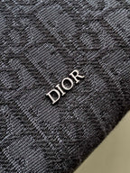 Dior mini crossbody bag detail with embroidered Dior lettering on dark fabric