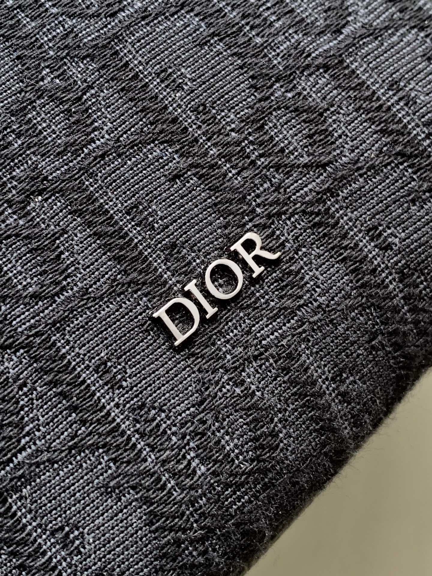 Dior mini crossbody bag detail with embroidered Dior lettering on dark fabric