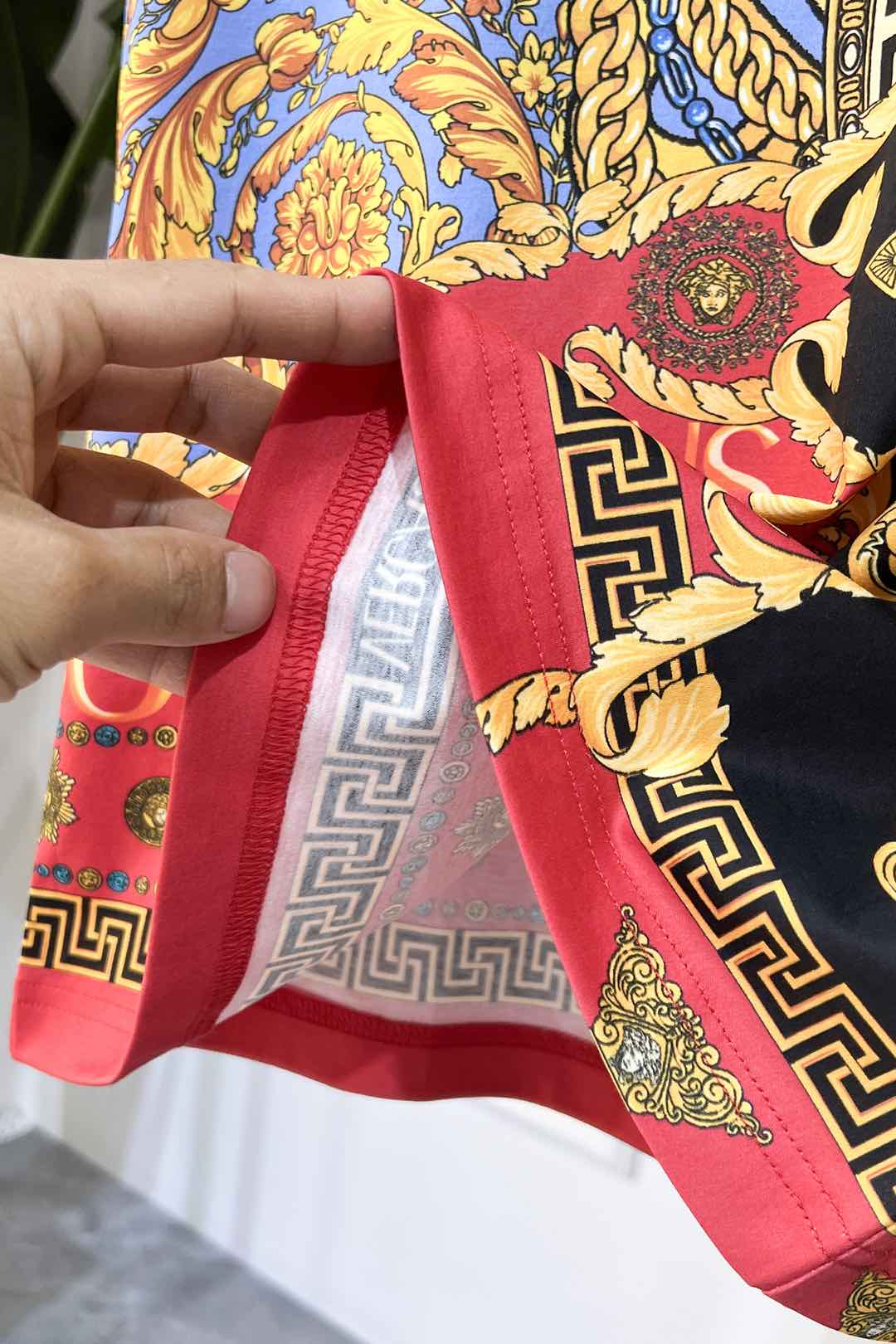 Crewneck T-shirt hem detail with red trim and multicolor baroque logo print