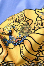Close-up of light blue crewneck T-shirt with gold baroque figure and jeweled details