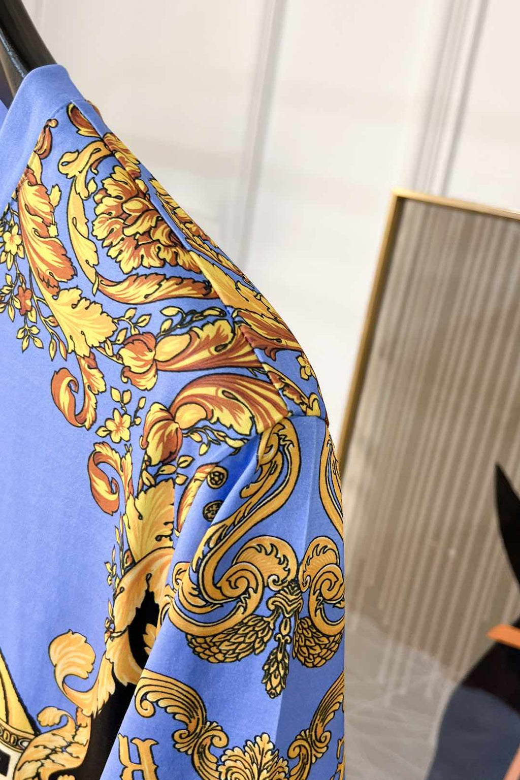 Side view of light blue crewneck T-shirt with blue and gold baroque sleeve pattern