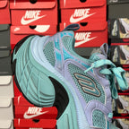 Teal athletic sneaker with lavender overlays, mesh panels, and turquoise laces
