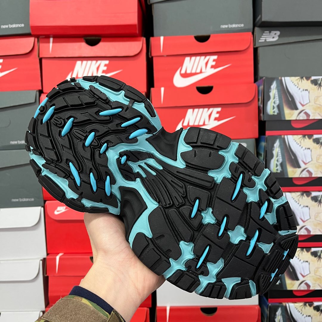 Black outsole with teal traction pods on athletic sneaker bottom