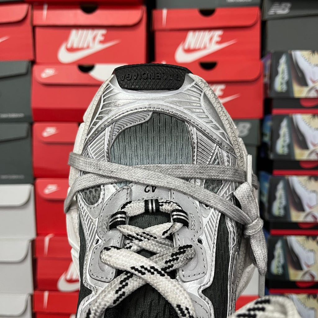 Close-up of lace-up shoe upper with black tongue lining and silver patterned panels