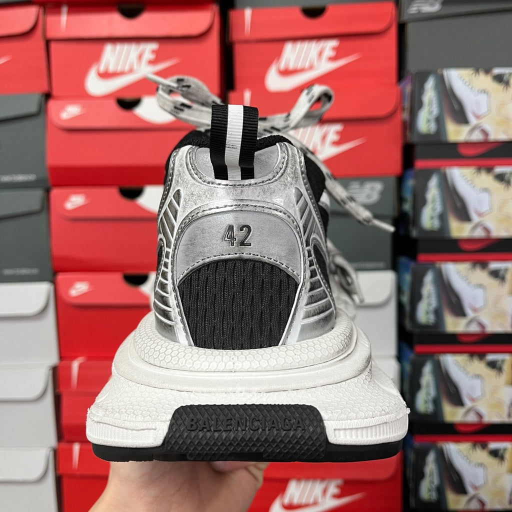 Back view of lace-up sneakers with black tongue, silver upper, and BALENCIAGA on heel