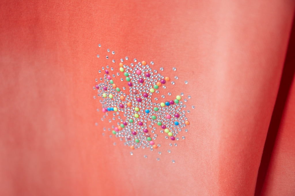 Coral orange T-shirt with sparkling multicolor rhinestone floral emblem